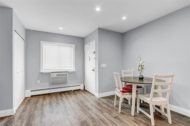 dining space featuring a baseboard heating unit, a wall unit AC, and light wood-type flooring