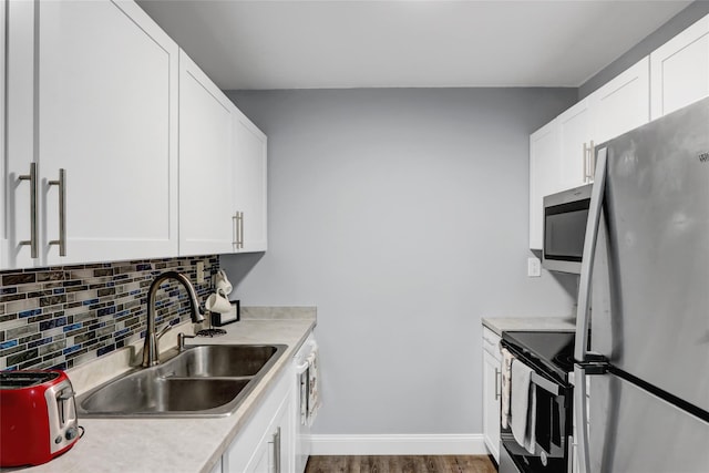 kitchen with white cabinetry, appliances with stainless steel finishes, sink, and hardwood / wood-style floors