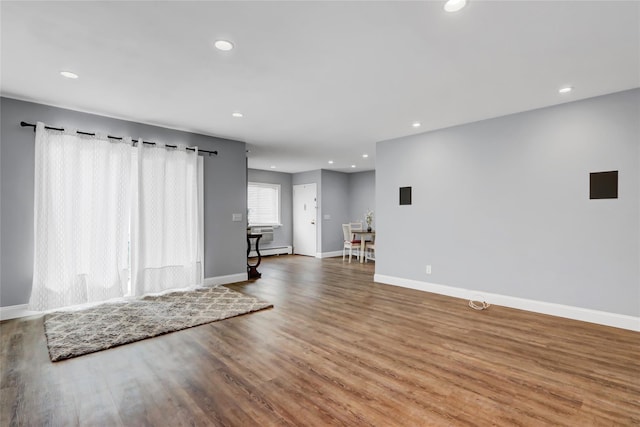 unfurnished living room featuring wood-type flooring and a baseboard radiator