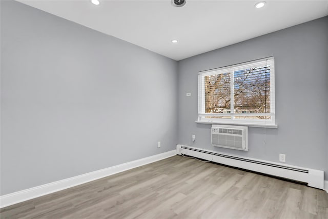 spare room with a wall mounted AC, baseboard heating, and light hardwood / wood-style floors