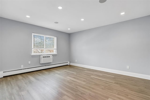 unfurnished room featuring an AC wall unit, a baseboard heating unit, and light hardwood / wood-style floors