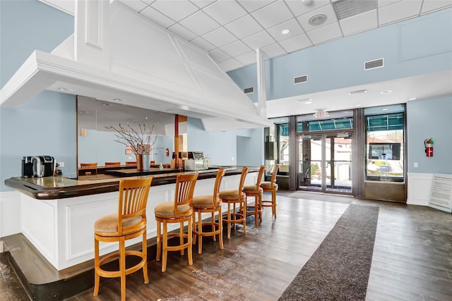 bar with french doors, white cabinets, dark hardwood / wood-style floors, and a high ceiling