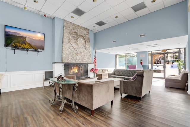 living room with dark hardwood / wood-style floors, a paneled ceiling, and a fireplace