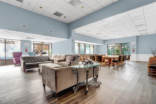 living room featuring wood-type flooring, a wealth of natural light, and a paneled ceiling