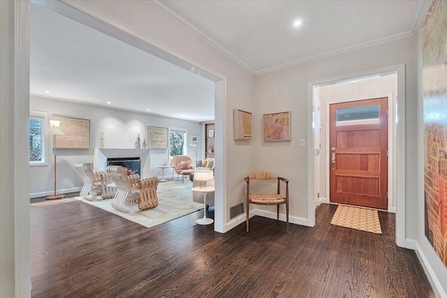 foyer featuring dark wood-style floors, baseboards, a lit fireplace, and ornamental molding