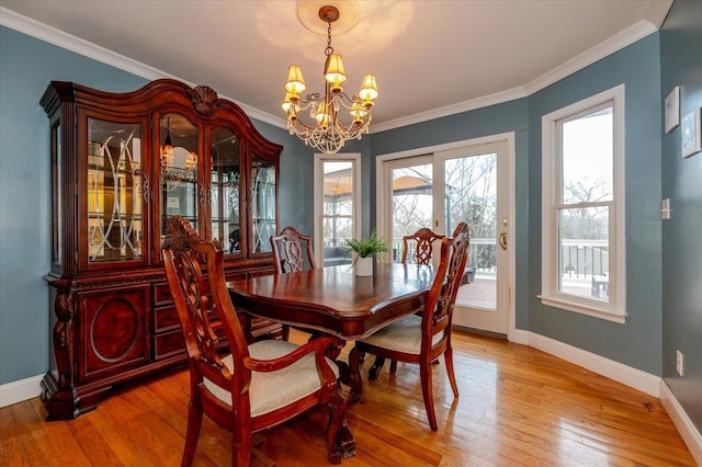 dining space featuring ornamental molding, wood-type flooring, and a notable chandelier