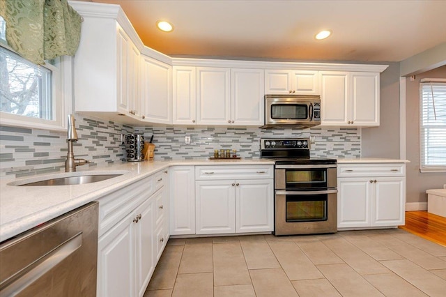 kitchen with appliances with stainless steel finishes, sink, and white cabinets