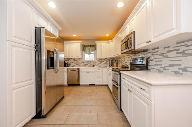 kitchen featuring white cabinetry, appliances with stainless steel finishes, decorative backsplash, and light tile patterned floors