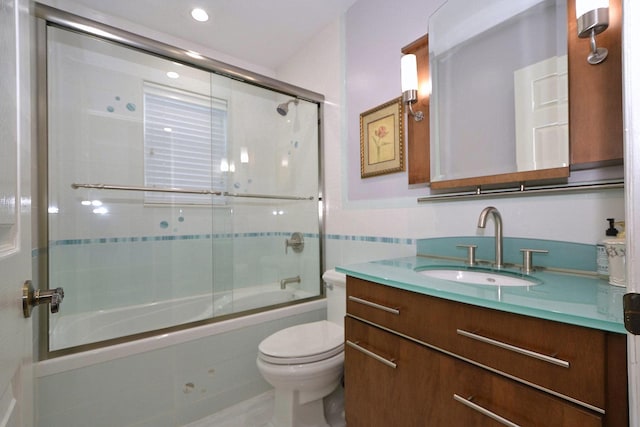 full bathroom featuring vanity, tile walls, shower / bath combination with glass door, and toilet