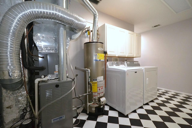 laundry room featuring water heater, washing machine and clothes dryer, and cabinets