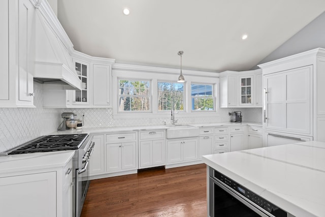 kitchen featuring decorative light fixtures, sink, white cabinets, light stone counters, and stainless steel appliances