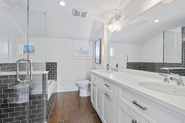 full bathroom featuring shower with separate bathtub, wood-type flooring, lofted ceiling, vanity, and toilet