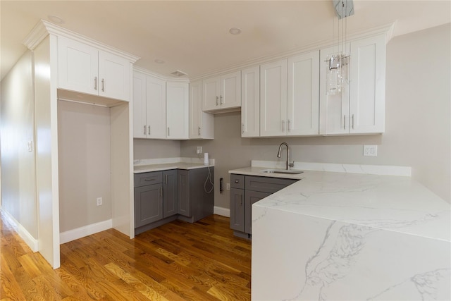 kitchen with white cabinets, decorative light fixtures, sink, and light wood-type flooring