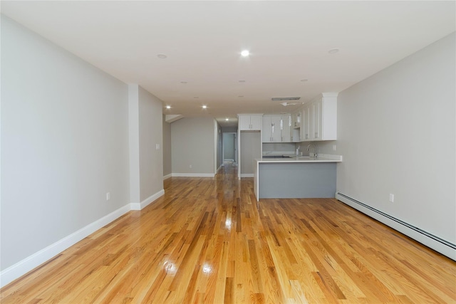 unfurnished living room with sink, a baseboard radiator, and light hardwood / wood-style floors