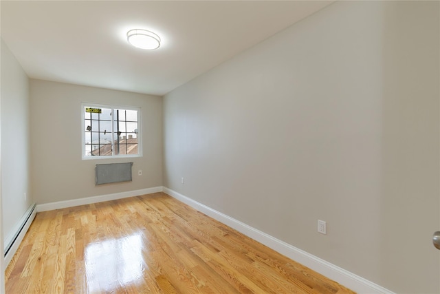 spare room featuring a baseboard radiator and light wood-type flooring