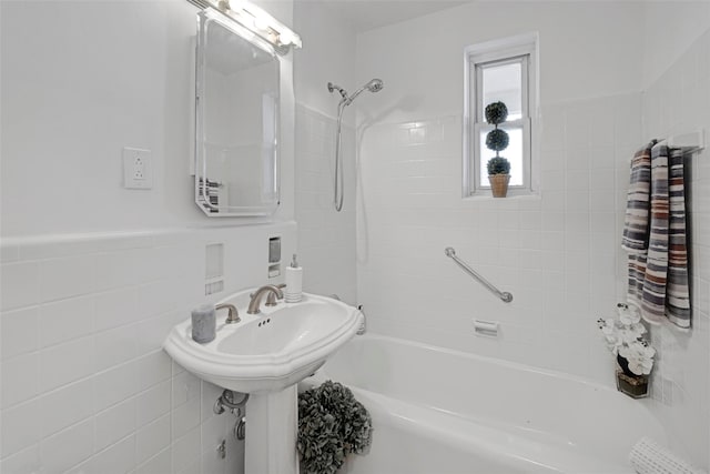 bathroom with tiled shower / bath combo and tile walls