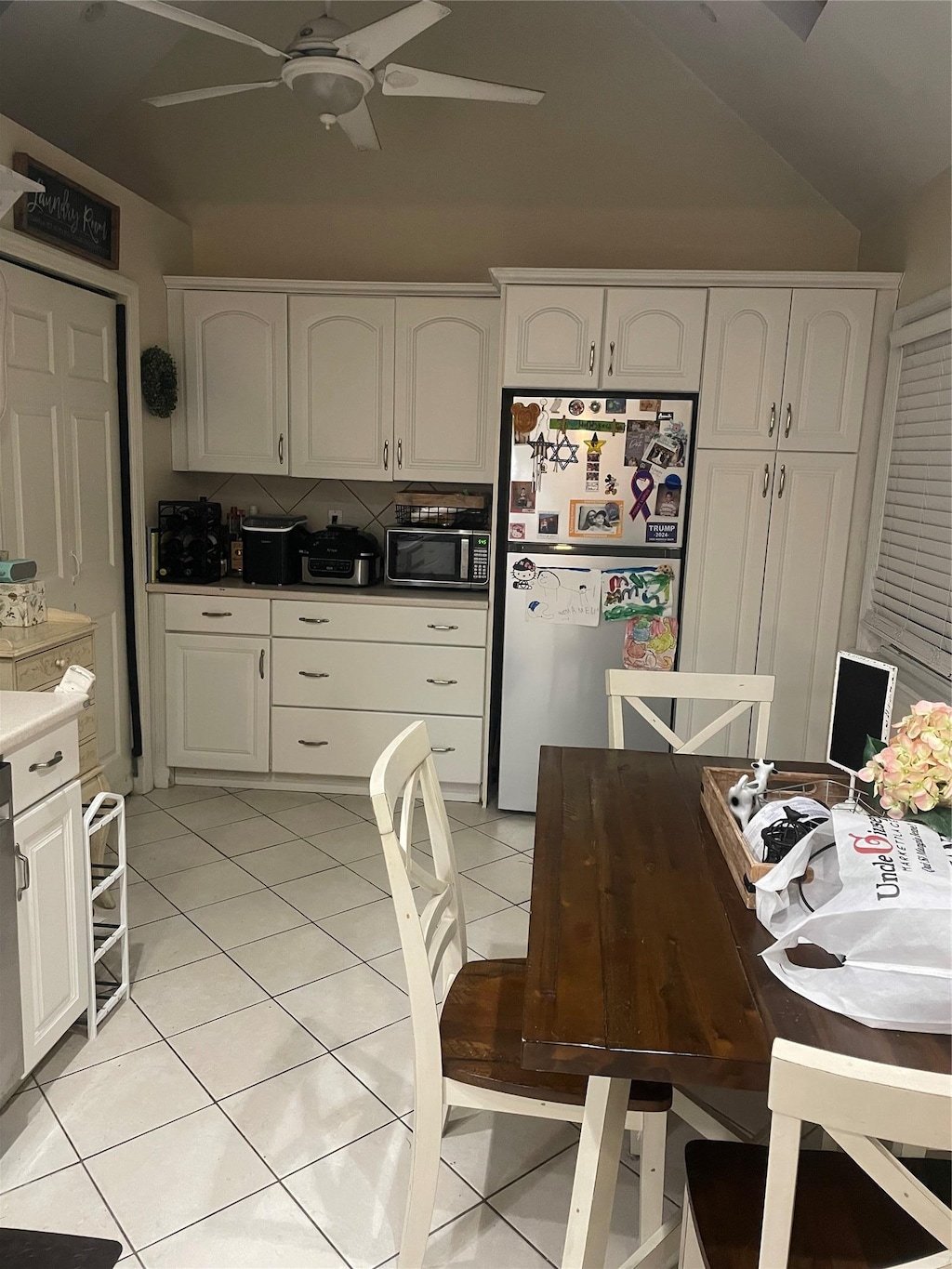 kitchen with stainless steel fridge, ceiling fan, white cabinetry, backsplash, and light tile patterned flooring