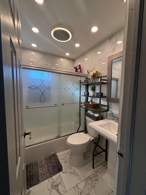 full bathroom featuring enclosed tub / shower combo, sink, and toilet