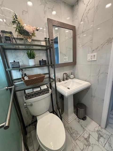 bathroom with toilet and tile walls