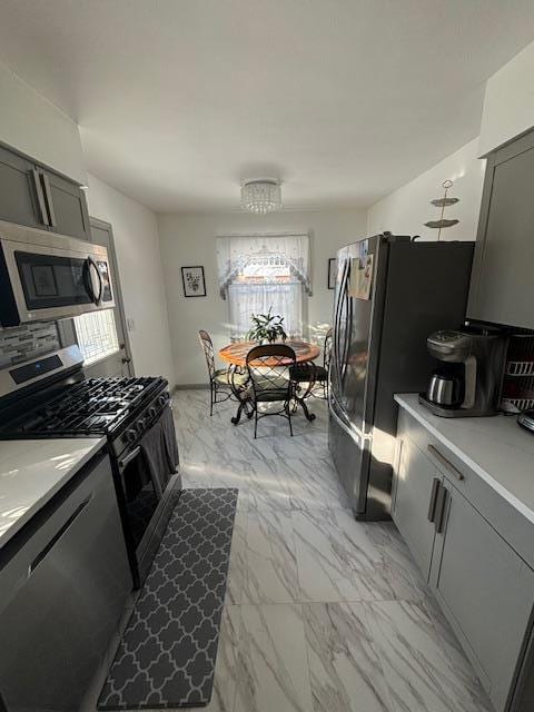 kitchen with gray cabinetry, tasteful backsplash, and stainless steel appliances