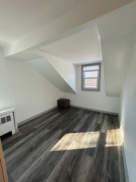 bonus room with lofted ceiling and dark hardwood / wood-style flooring