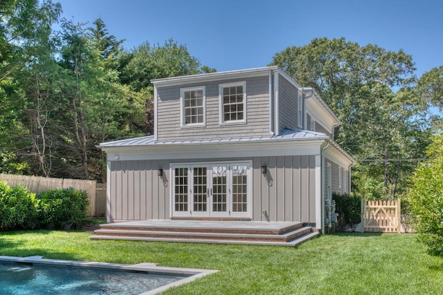 rear view of property with a fenced in pool, an outdoor structure, and a lawn