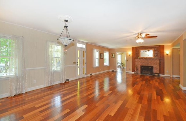 unfurnished living room featuring ceiling fan, crown molding, hardwood / wood-style floors, and a fireplace