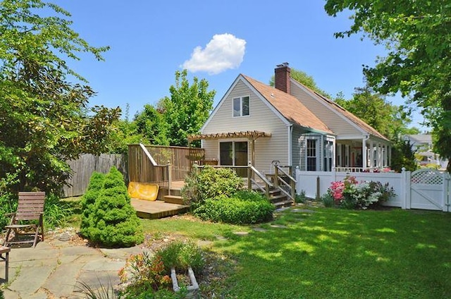 rear view of property with a wooden deck, a lawn, and a patio area