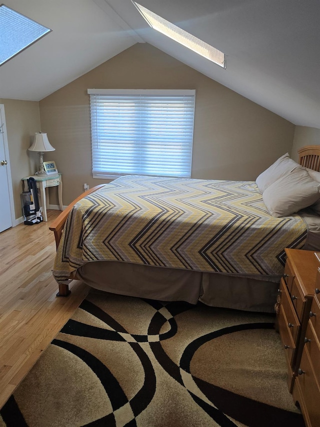 bedroom with lofted ceiling with skylight and hardwood / wood-style floors