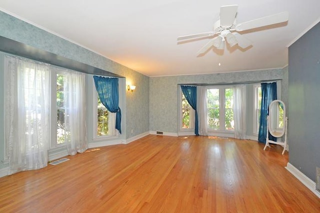 unfurnished room with a wealth of natural light, visible vents, baseboards, and wood finished floors