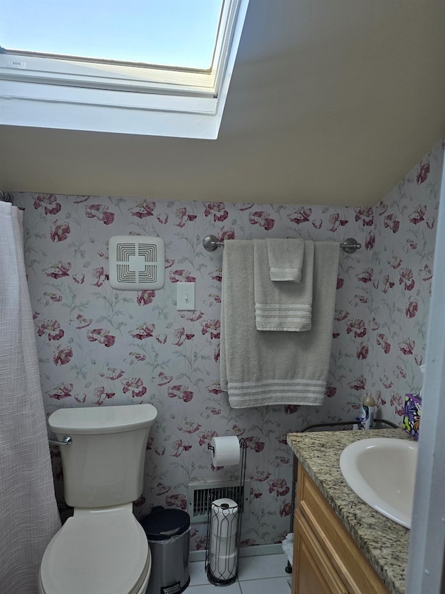 bathroom featuring a skylight, wallpapered walls, toilet, vanity, and tile patterned floors