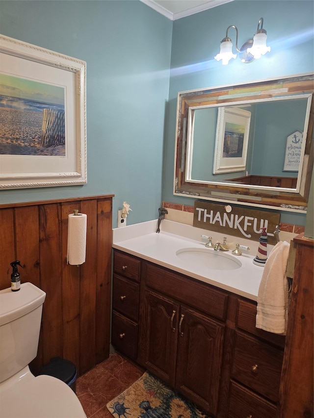 half bath with ornamental molding, vanity, and toilet