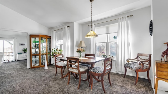 dining space featuring lofted ceiling and dark carpet