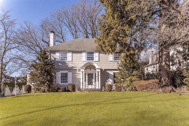 view of front of house with a front lawn, a chimney, and fence