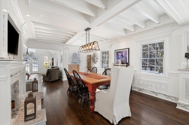 dining area featuring dark wood-type flooring, beamed ceiling, ornamental molding, and a chandelier