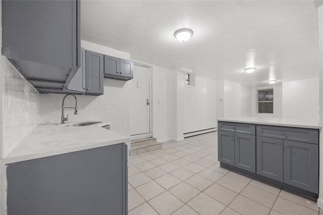 kitchen with sink, gray cabinetry, tasteful backsplash, light tile patterned floors, and baseboard heating