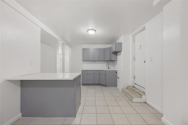 kitchen featuring gray cabinets, light tile patterned flooring, sink, and kitchen peninsula