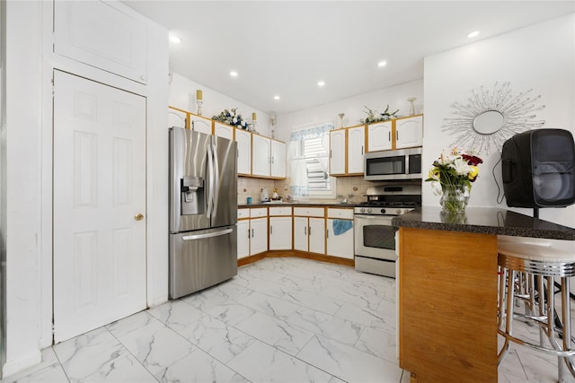 kitchen with white cabinetry, a kitchen breakfast bar, decorative backsplash, kitchen peninsula, and stainless steel appliances