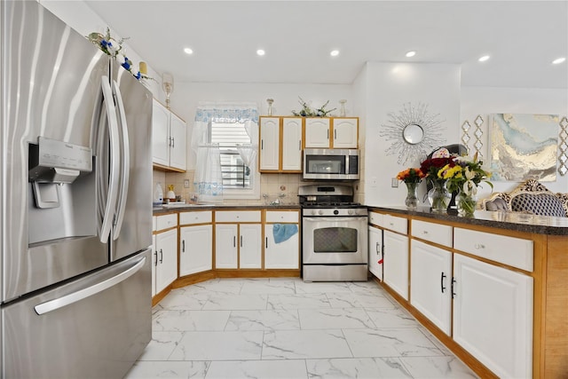 kitchen with backsplash, stainless steel appliances, and white cabinets