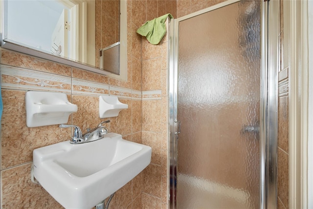 bathroom featuring a shower with door and sink