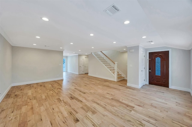 interior space with crown molding, lofted ceiling, and light hardwood / wood-style flooring