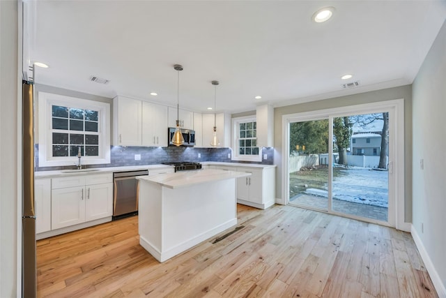 kitchen with sink, white cabinetry, a center island, pendant lighting, and stainless steel appliances