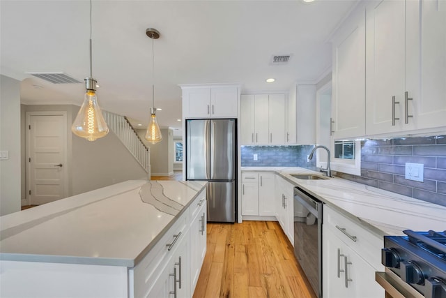 kitchen with white cabinetry, appliances with stainless steel finishes, sink, and pendant lighting