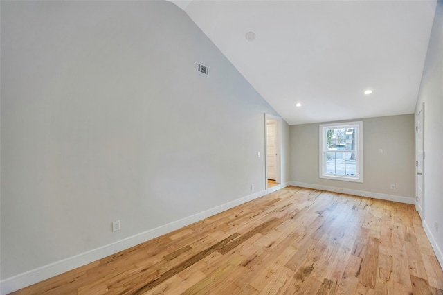 empty room with light hardwood / wood-style floors and vaulted ceiling