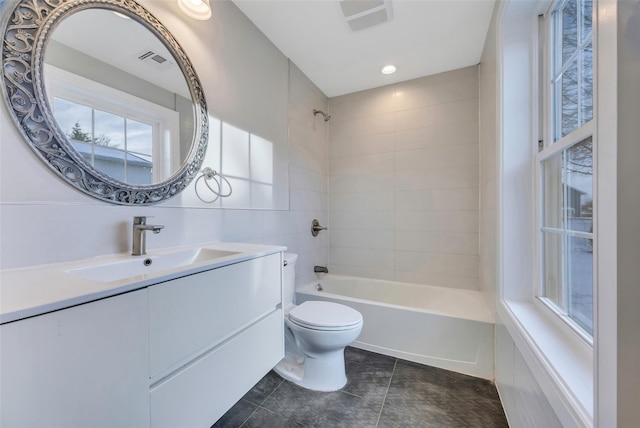 full bathroom featuring vanity, toilet, tiled shower / bath combo, and tile patterned flooring