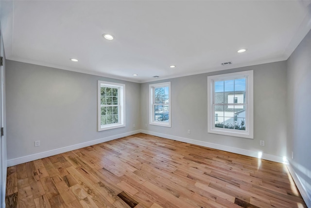 spare room with ornamental molding, a healthy amount of sunlight, and light wood-type flooring