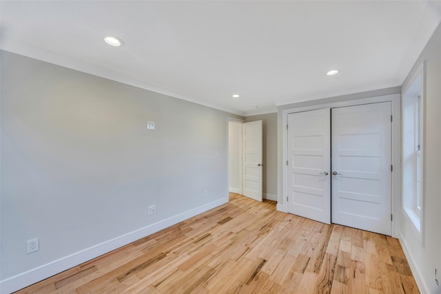 unfurnished bedroom featuring crown molding, a closet, and light wood-type flooring