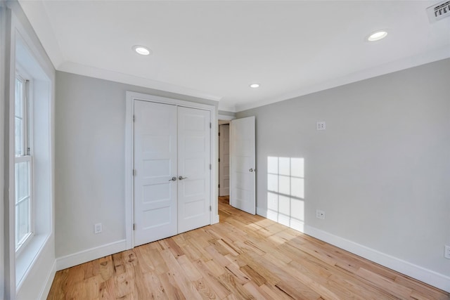 unfurnished bedroom featuring crown molding, light hardwood / wood-style floors, and a closet