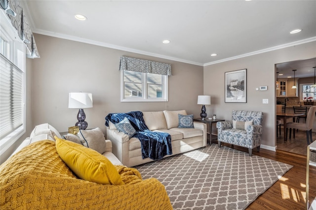 living room with a wealth of natural light, ornamental molding, and wood-type flooring