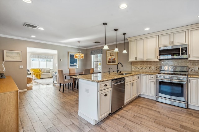 kitchen featuring sink, light stone counters, kitchen peninsula, pendant lighting, and stainless steel appliances